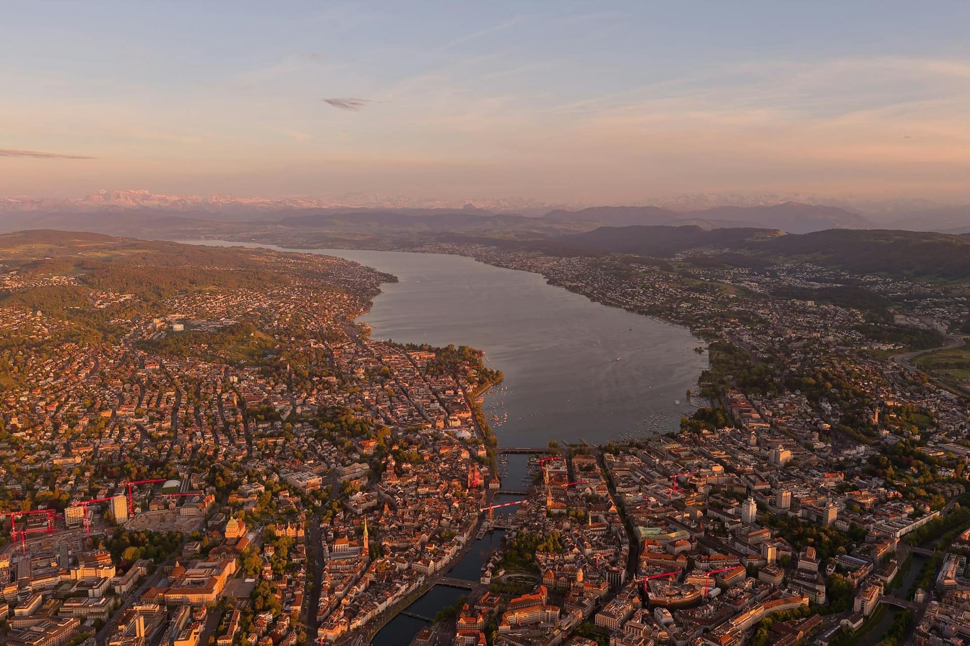 Luftaufnahme der Stadt Zürich mit dem Zürichsee bei Sonnenuntergang.